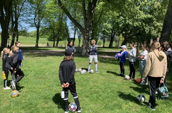 A photo of young people in sportswear in a circle, learning about FootGolf.