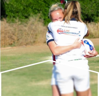 Two female footgolf players embracing on a golf course.