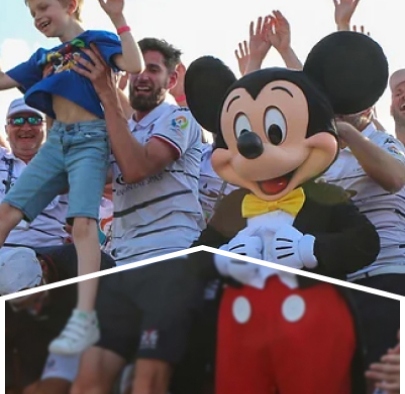 A group of people cheering next to a Mickey Mouse mascot.
