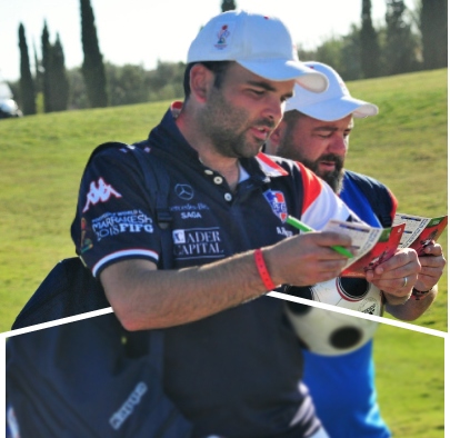Close-up of two men reviewing scorecards on a golf course.