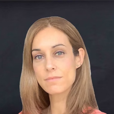 A close headshot of a blond woman in a pink shirt.