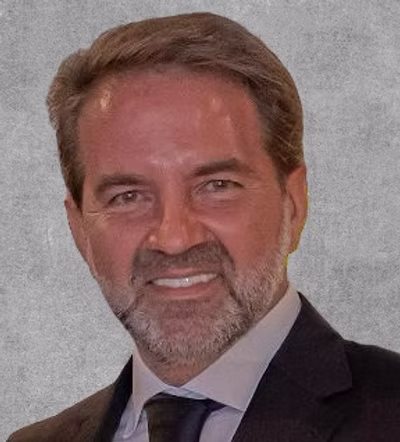 A man in a black suit smiling.