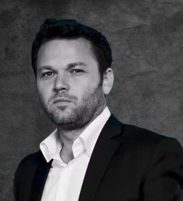 Black and white close-up photo of a man in a black suit.