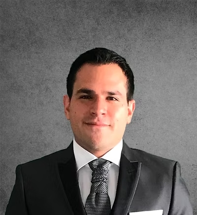 A portrait photo of a smiling man in a black suit and tie.