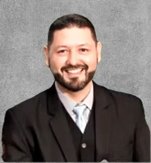 A portrait photo of a smiling man in a black suit and a white tie.