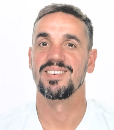 A close-up headshot of a smiling man in a white T-shirt.