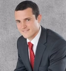 Portrait photo of a smiling man in a black suit and red tie.