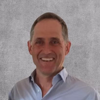 A close-up portrait photo of a smiling man in a blue shirt.